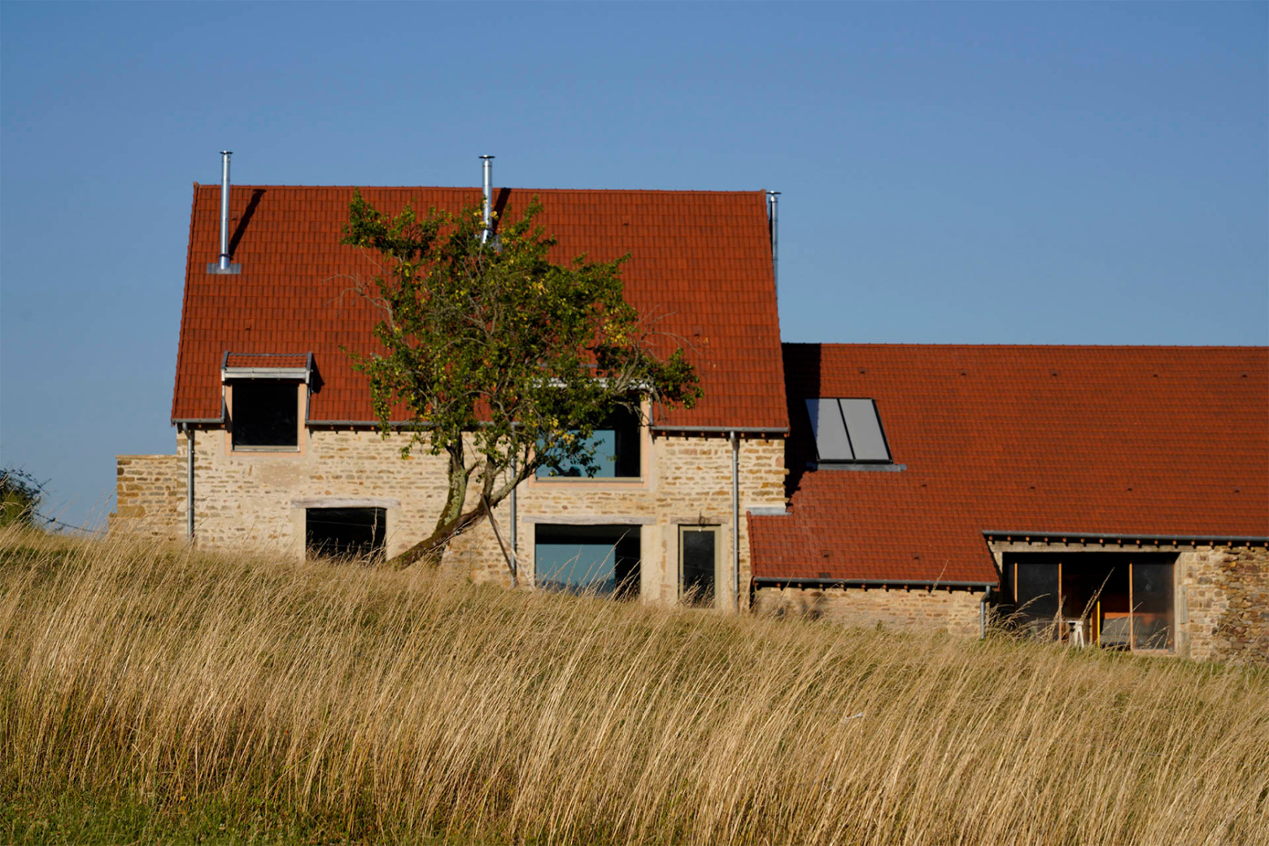 Das alte Bauernhaus öffnet sich mit deutlich größeren Fenstern nach außen als zuvor. Die charakteristische Natursteinarchitektur blieb jedoch erhalten. © Charles Petillon 