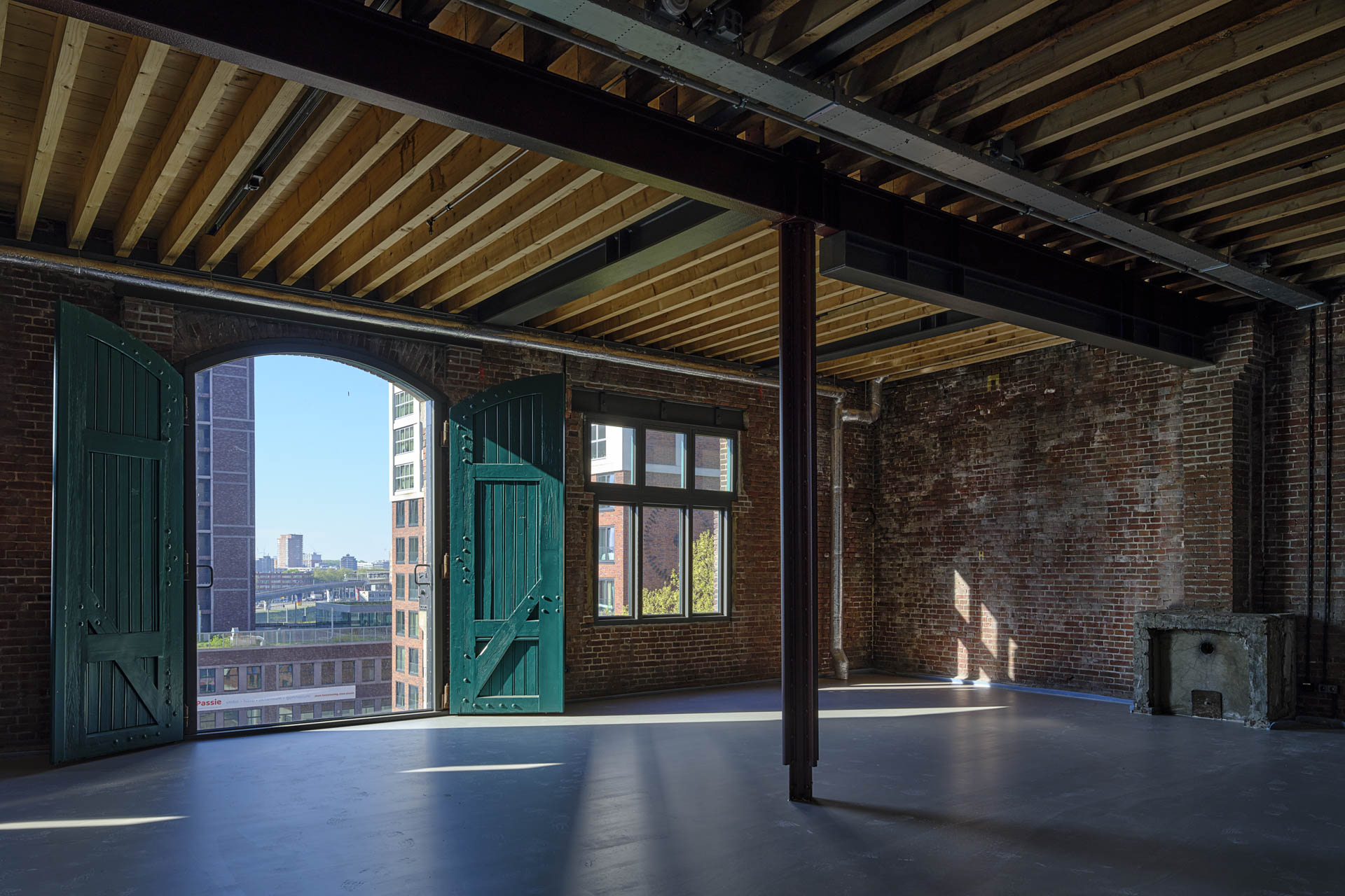 Der Innenraum hat große verglaste Öffnungen in der Hauptfassade, mit nach innen öffnenden, grünen Fensterläden. Der Boden ist aus Beton, und gefärbte Stahlstützen sowie Stahlträger prägen den Raum. Die Wände bestehen aus Backstein.