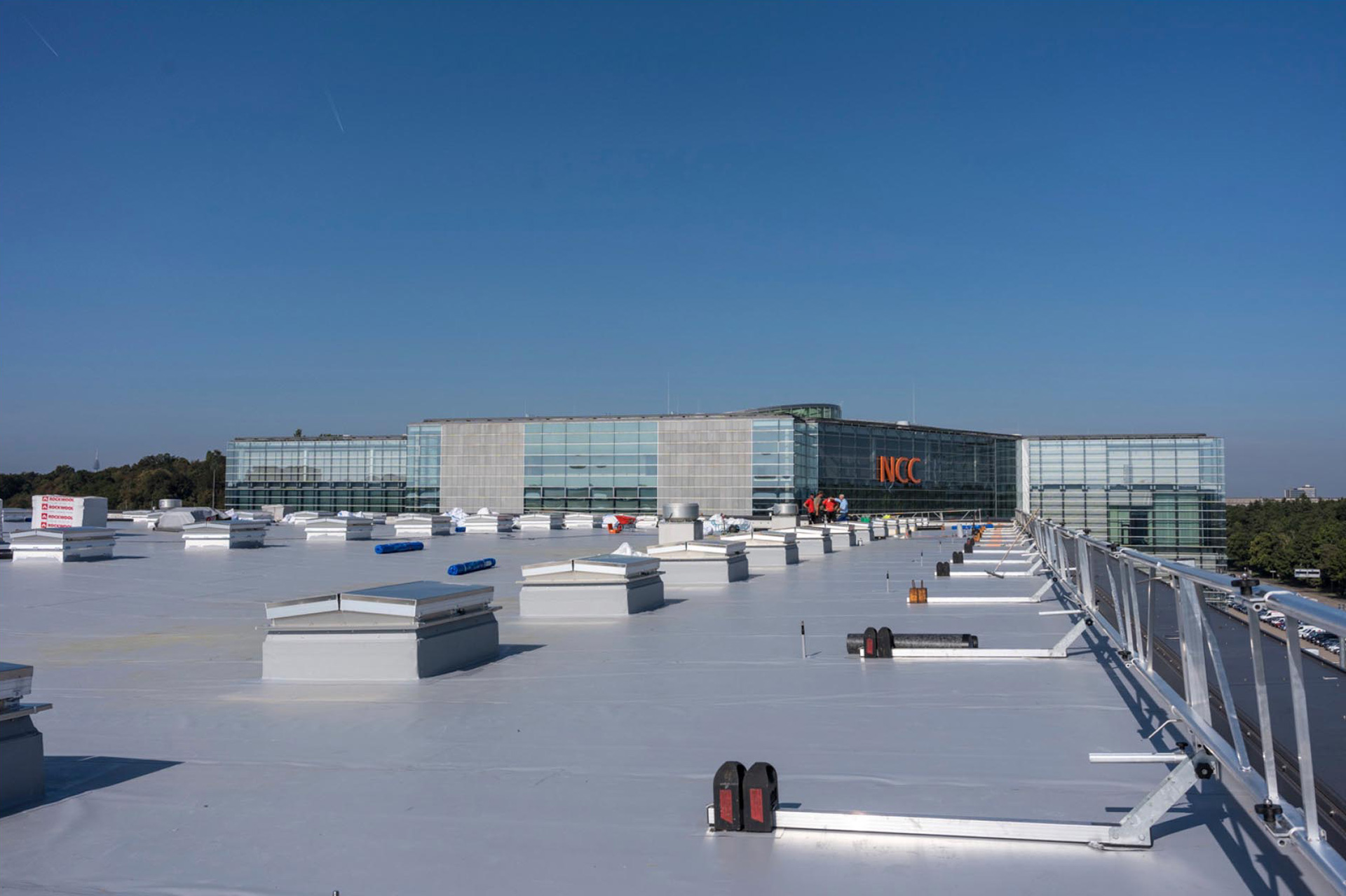 Flachdach einer Messehalle mit Dachluken. Im Hintergrund ist ein h&ouml;heres Messegeb&auml;ude zu sehen.