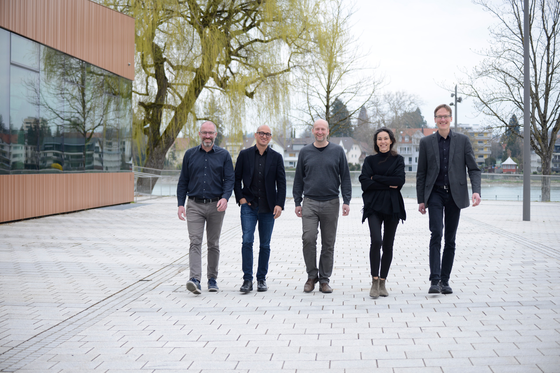 Die vier M&auml;nner und eine Frau der VELUX Jury laufen einen gepflasterten Weg entlang.